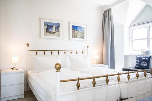 a white bedroom with a white bed and a window at App. Hegger Inselglück in Westerland (Sylt)