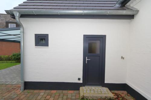 ein weißes Haus mit einer schwarzen Tür drauf in der Unterkunft Solveig Fynn 04 in Westerland