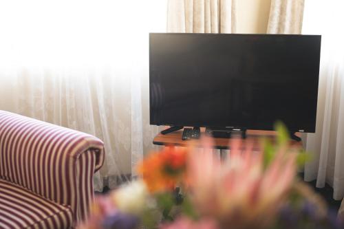 a flat screen tv sitting on a table next to a couch at Oak lodge Guest House in Grahamstown