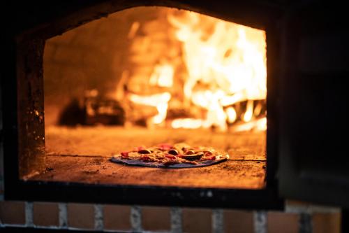 a pizza baking in an oven with a fire at Craveiral Farmhouse by Belong Staying & Feeling in São Teotónio