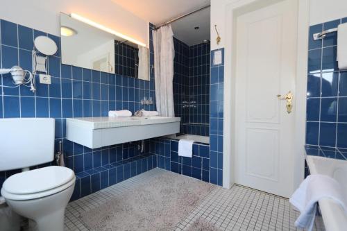 a blue tiled bathroom with a toilet and a sink at Teewelkenhüs Sonnenappartement in Archsum
