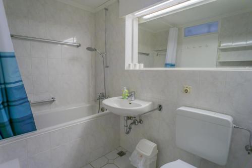 een badkamer met een wastafel, een toilet en een spiegel bij Metropol 276 in Westerland