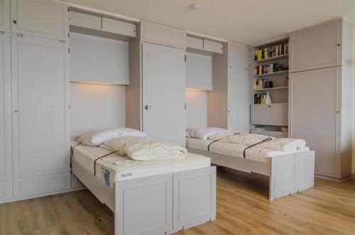 two beds in a room with white walls and wooden floors at Haus Sylter Welle 9-91 WB in Westerland (Sylt)