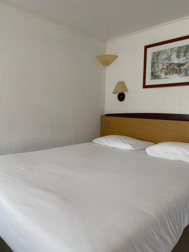 Hôtel Campanile Cahors في كاهور: غرفة نوم بسريرين بيض وصورة على الحائط