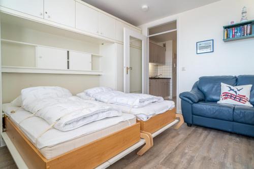 a room with two beds and a blue couch at Haus Sylter Welle 10-105 WB in Westerland (Sylt)
