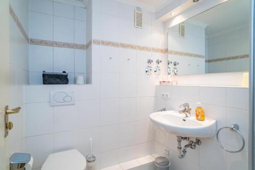 a white bathroom with a sink and a toilet at Haus Sylter Welle 10-105 WB in Westerland (Sylt)