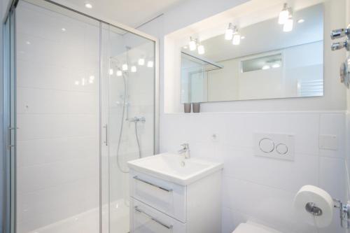 uma casa de banho branca com um lavatório e um chuveiro em Haus Metropol 196 OB em Westerland