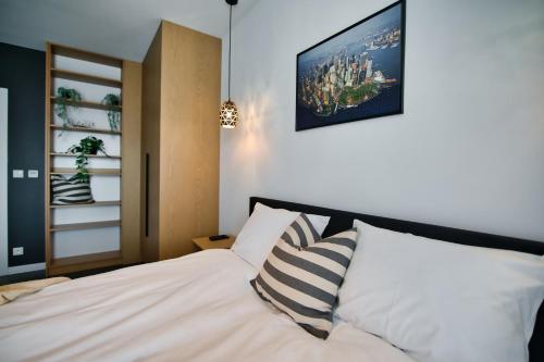 um quarto com uma cama branca com almofadas listradas em Apartamenty Laguna Beskidów - A33 em Zarzecze
