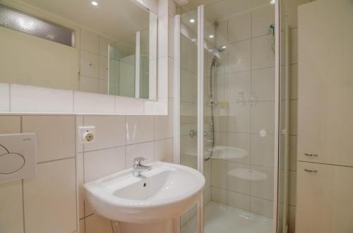 biała łazienka z umywalką i prysznicem w obiekcie Haus Sylter Welle 5-49 OB w mieście Westerland
