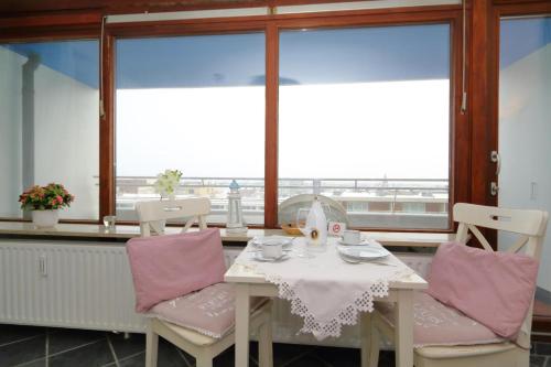 uma mesa e cadeiras com uma mesa e janelas em Haus Sylter Welle 6-60 OB em Westerland