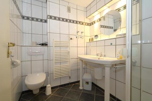 uma casa de banho branca com um WC e um lavatório em Haus Sylter Welle 6-60 OB em Westerland