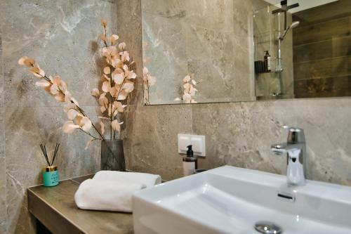 uma casa de banho com um lavatório e um vaso com flores em Apartamenty Laguna Beskidów - A33 em Zarzecze