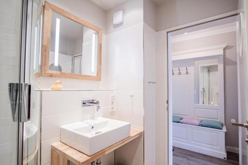 uma casa de banho branca com um lavatório e um espelho em App. Theo 50 em Westerland