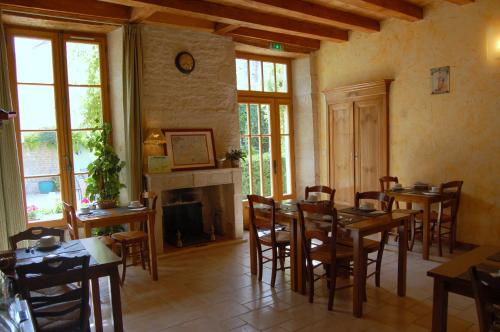une salle à manger avec des tables, des chaises et une cheminée dans l'établissement Hôtel du Donjon, à Aulnay