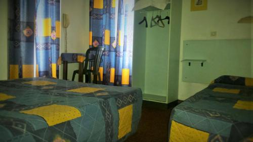 a room with two beds and a table and chairs at Hôtel du Château Fort in Lourdes