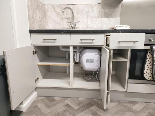 uma cozinha com armários brancos e um lavatório em Local to Russells Hall Hospital em Brierley Hill