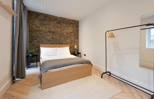sypialnia z łóżkiem i ceglaną ścianą w obiekcie The Battersea Scenery - Elegant 2BDR Flat w Londynie