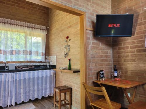 a dining room with a table and a television on the wall at Chalé Petra - Recanto da Pedra in São Bento do Sapucaí