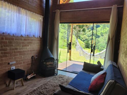 a living room with a couch and a large window at Chalé Petra - Recanto da Pedra in São Bento do Sapucaí