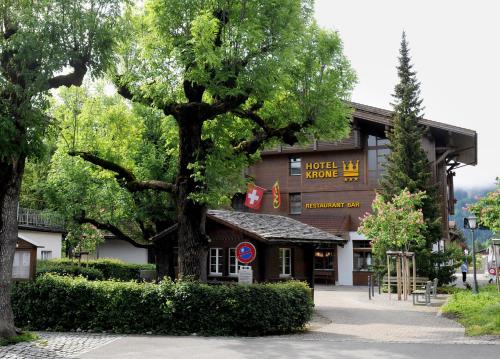 un bâtiment avec un grand arbre devant lui dans l'établissement Hotel Krone Lenk, à Lenk im Simmental