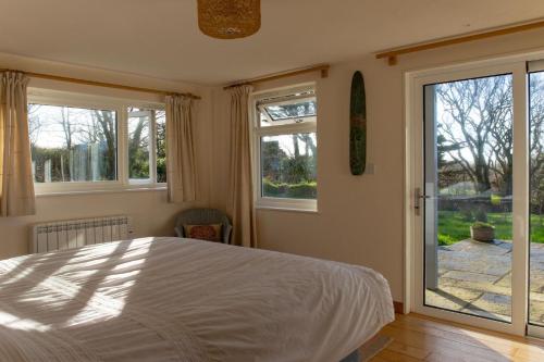 a bedroom with a bed and two windows and a door at The Orchard in Hartland