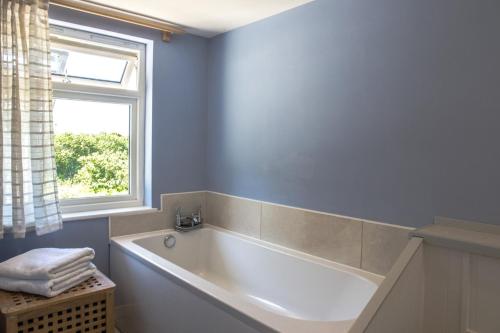 a bathroom with a white tub and a window at The Orchard in Hartland
