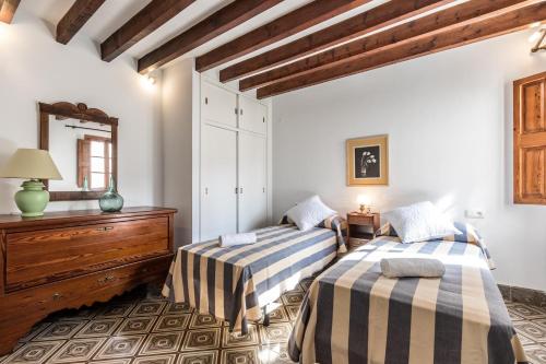 two beds in a room with a mirror and a dresser at Historic Pollensa Townhouse - Casa Bugera - 3 Bedrooms - Private Pool - Walking Distance to Centre in Pollença