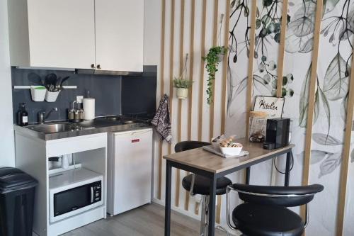 une petite cuisine avec une table et des chaises. dans l'établissement HSH FRANCE LOCATION Disney Land PARIS - Suite Nicolas - Appartement de charme, à Bussy-Saint-Georges