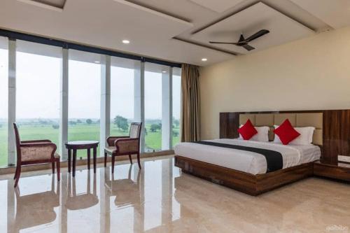 a bedroom with a bed and chairs and windows at The Park, Itarsi in Itārsi