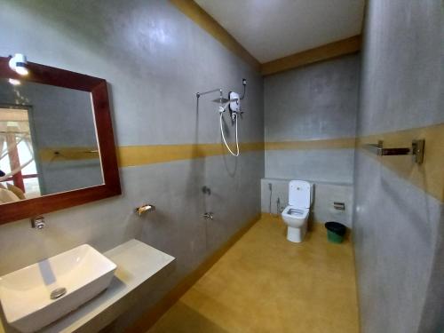 a bathroom with a sink and a toilet and a mirror at The Mango House Ahangama in Ahangama