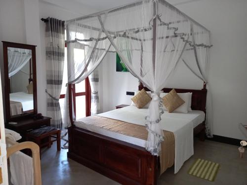 a bedroom with a canopy bed and a mirror at The Mango House Ahangama in Ahangama