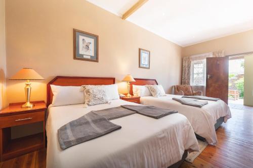 a bedroom with two beds and a table with lamps at Oak lodge Guest House in Grahamstown