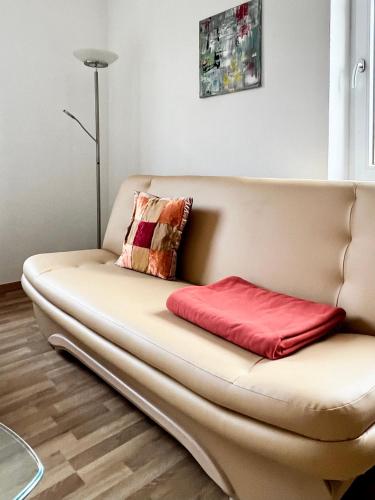 a couch in a living room with a red pillow at Göltzschtal Apartment in Mylau