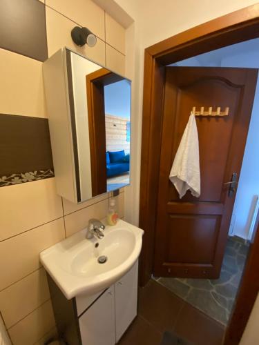 a bathroom with a sink and a mirror and a door at Apartament Zakopane Kościelisko in Kościelisko