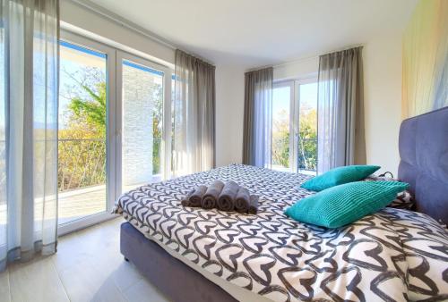 a bedroom with a bed with blue pillows and windows at Villa Valle in Sveti Vid-Miholjice
