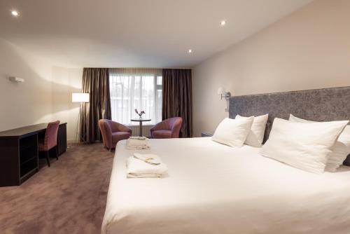 una camera d'albergo con un grande letto bianco e una scrivania di Landgoed de Rosep a Oisterwijk