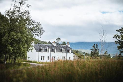 a white house with a gray roof in a field at Coulin Farmhouse in Kinlochewe