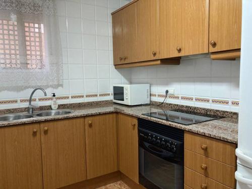 uma cozinha com armários de madeira, um lavatório e um micro-ondas em Apartamento en Montanejos em Montanejos