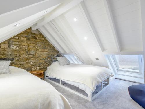 two beds in a attic bedroom with a stone wall at 2 Bed in Ogmore-by-Sea 86495 in Southerndown