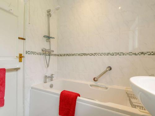 a bathroom with a tub and a sink and a red towel at 1 Bed in Ashford-in-the-Water 87471 in Great Longstone