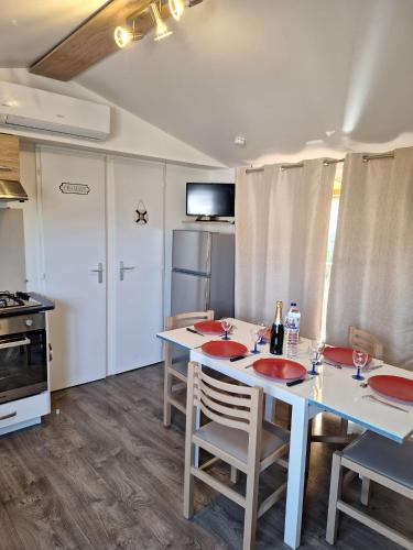 a kitchen with a table and chairs and a refrigerator at Mobile home Chic in Canet-en-Roussillon