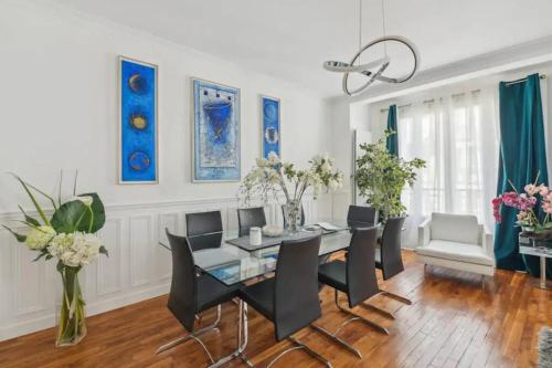 une salle à manger avec une table en verre et des chaises noires dans l'établissement Luxe à la francaise 75017, à Paris