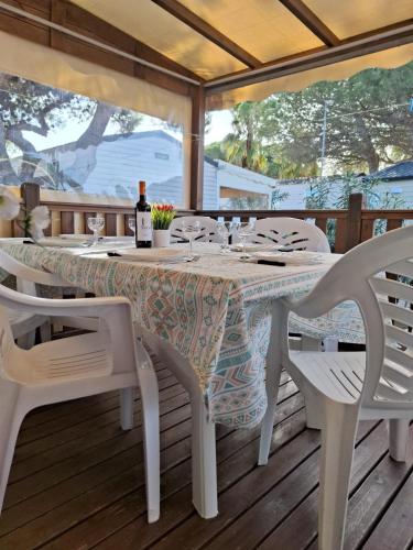 stół z krzesłami i butelkę wina na tarasie w obiekcie Mobile home Chic w mieście Canet-en-Roussillon
