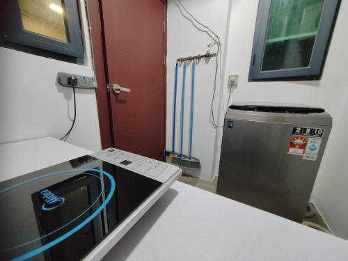uma cozinha com um micro-ondas e um frigorífico em Aell Homestay Vivacity em Kuching