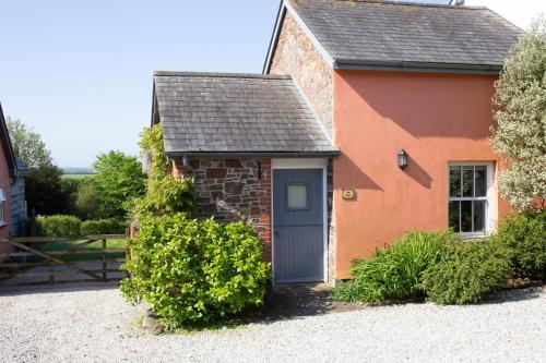 una pequeña casa roja y naranja con una puerta azul en The Dairy, en Hartland