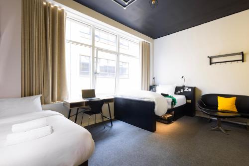 una camera d'albergo con due letti, una scrivania e una finestra di REZz Dublin a Dublino