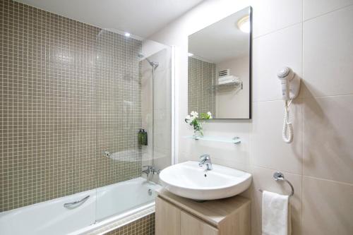 a bathroom with a sink and a tub and a mirror at Pierre & Vacances Sevilla in Seville