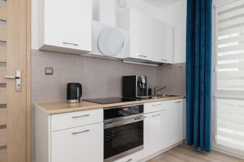 a kitchen with white cabinets and a stove top oven at Cracow Royal Blue Apartment Avia Estate by Renters in Kraków