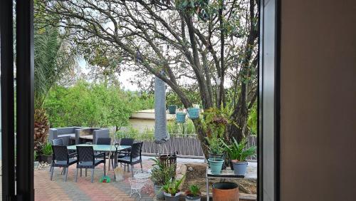 a patio with a table and chairs and a tree at The Haven: Make our Home your Home in Estcourt