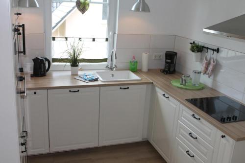 a kitchen with white cabinets and a sink and a window at Ferienwohnung Country in Born